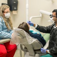 dentist examines patient with assistant (dental services)